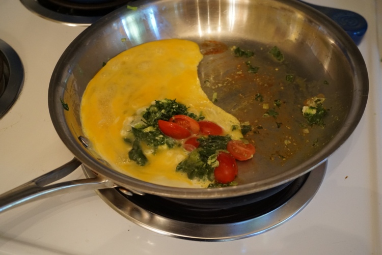 Spinach mixture cooking in with the eggs and tomatoes.